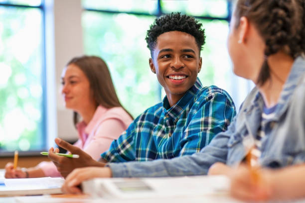 istock Smiling Black ethnicity male student talking with classmate in classroom 1279905104