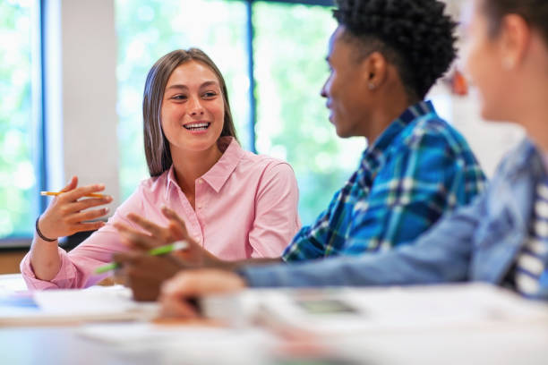 istock Smiling female student talking with classmate in classroom 1279905209