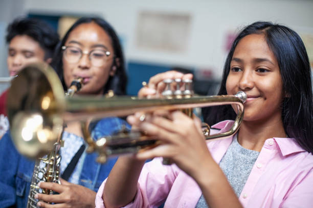 adolescente asiatica di etnia mista che suona la tromba in classe musicale a scuola - band name immagine foto e immagini stock