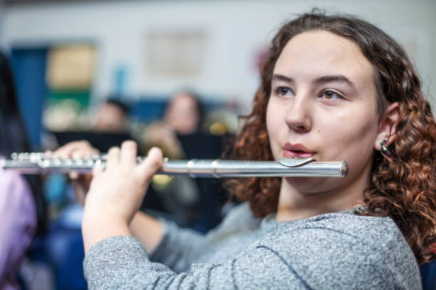 istock Brunette student playing flute in classroom in school 1279905617
