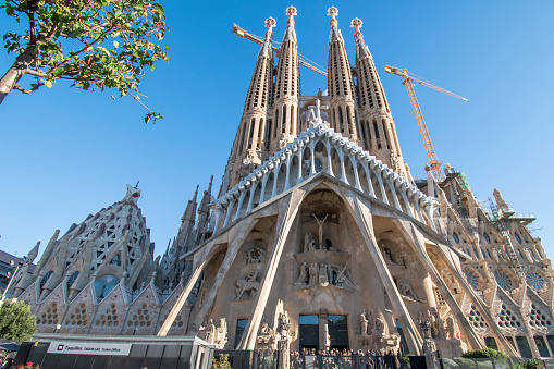 Barcelona, Catalonia, Spain - September 16th, 2013: Sagrada Familia Cathedral designed by famous architect Gaudi under blue summer sky with construction cranes, building up the cathedral towers. Catalonia, Barcelona, Spain, Europe