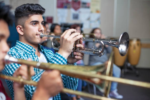 istock Male Middle Eastern ethnicity student practicing trumpet with friends in band class 1279906627