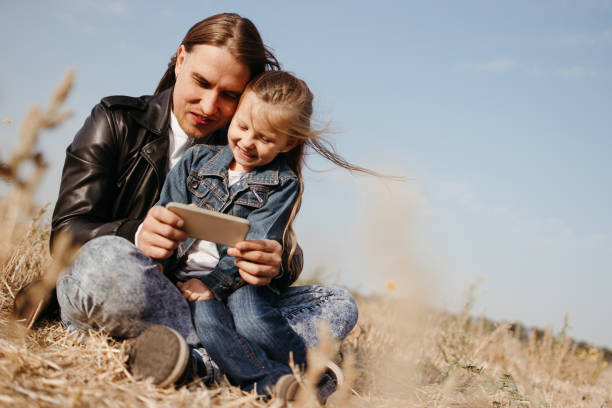 istock Father and daughter playing games with cell phone 1279907384