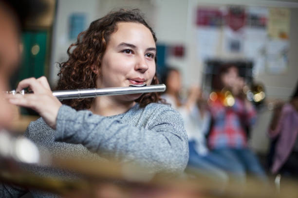 confident female brunette student practicing flute in band orchestra class