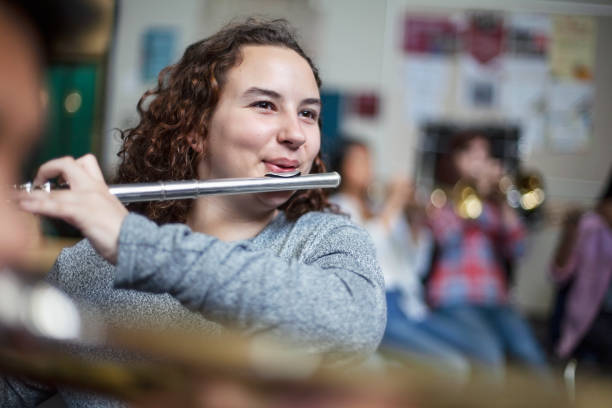 istock Confident female brunette student practicing flute in band orchestra class 1279908455