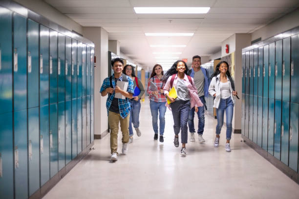 Diverse multi-ethnic teenage students running in hallway at school