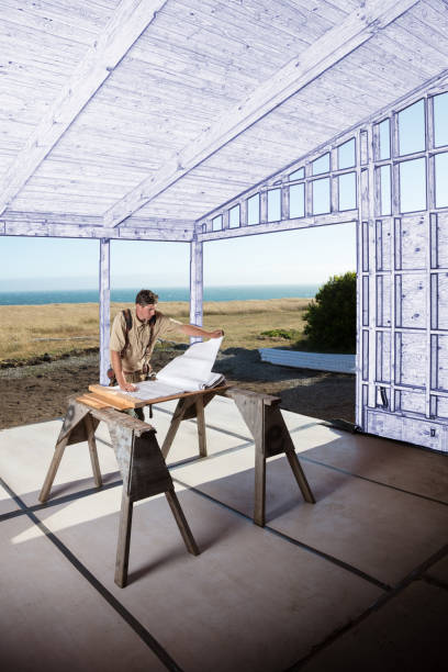 Carpenter construction worker building home using saw by ocean with blueprint technique on surrounding walls Carpenter construction worker building home using saw by ocean with blueprint technique on surrounding walls sawhorse stock pictures, royalty-free photos & images