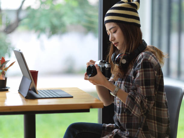 istock Female photographer holding digital camera while sitting in cafe 1279915916