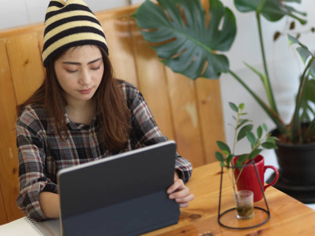 istock Female student using digital tablet on wooden table in cafe 1279915980