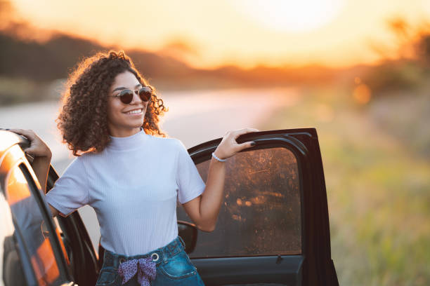 Teenager out of the car enjoying the sunset Teenager girl, Vacation, Happiness, Road, Nature teenagers only photos stock pictures, royalty-free photos & images