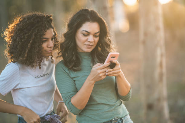 Mother and daughter using phone in the forest