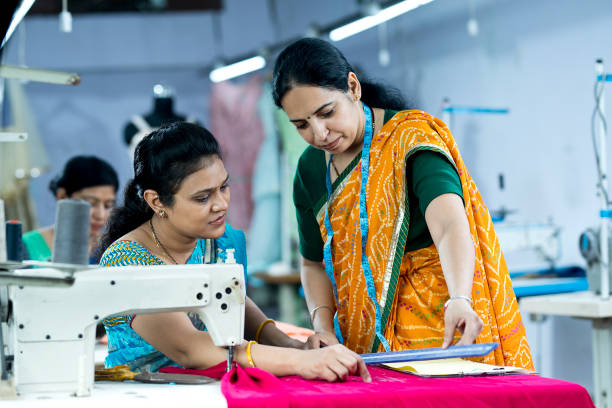 istock Inspector guiding female textile worker sewing garment on production line 1279927625