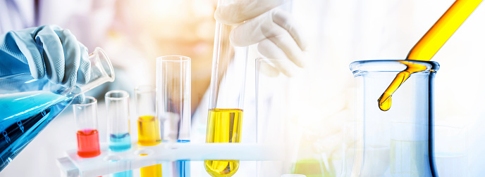 hand of scientist holding flask and pouring sample to test tube in chemical laboratory background, science laboratory research and development concept