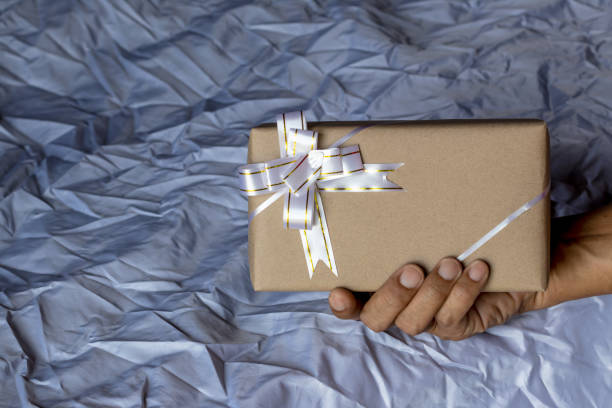 istock Hand holding gift box and bow tie canvas as a backdrop. 1279929311