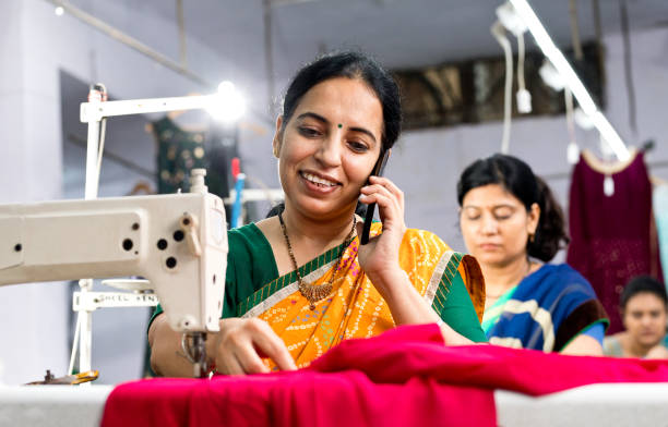 istock Indian woman textile worker talking on mobile phone while sewing dress fabric 1279930081