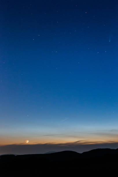 istock Moon and Neowise comet at dusk on a blue sky above mountains 1279930488