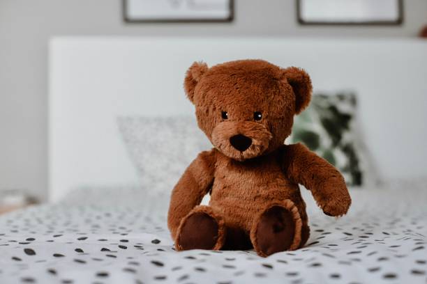 istock Cute little teddy bear sitting alone on a white bed. 1279932445