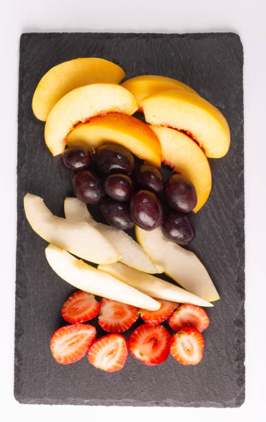 istock fresh fruit. strawberry, pear, grape and peach, cut on a stone slab 1279934725