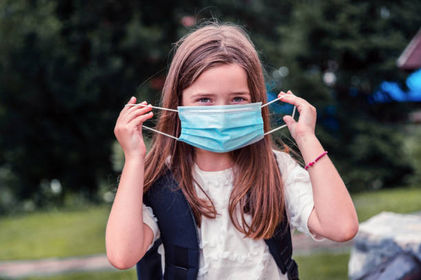 istock Smiling young girl putting on protective mask 1279935474