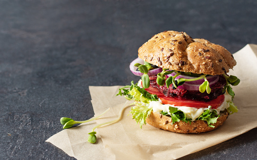 Vegan burger with beetroot cutlet and micro greens on black background.
