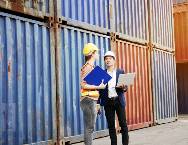 istock Young engineers standing in the shipping yard tracking the cargo inventory and checking container box for safety. 1279938126