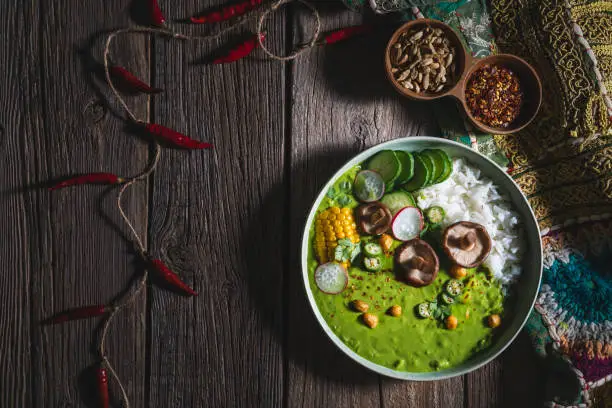 Thai green curry vegan bowl with basmati rice and corn, mushrooms, cucumber, chickpeas, radish, okra, coriander and chili peppers
