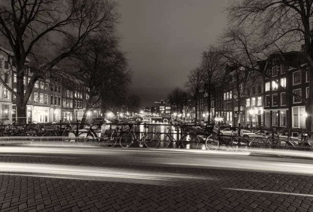 Canal bridge with traffic light trails at night in Amsterdam