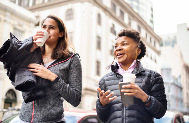 istock Smiling young friends talking over coffee while walking in the city 1279941678