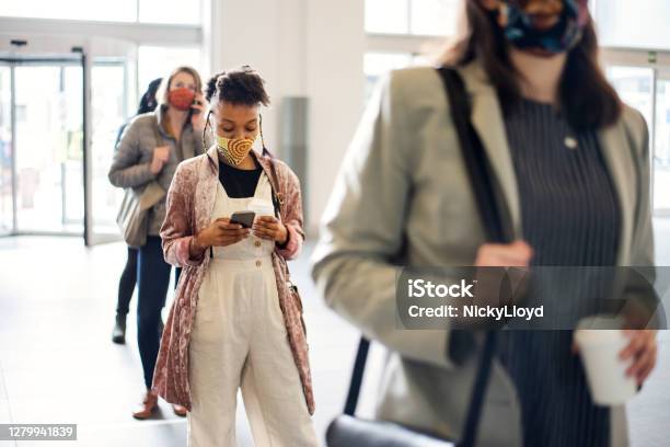 Woman In A Face Mask Social Distancing With People In A Lineup Stock Photo - Download Image Now