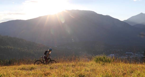 istock Female mountain e-biker rides up alpine meadow at sunrise 1279943393