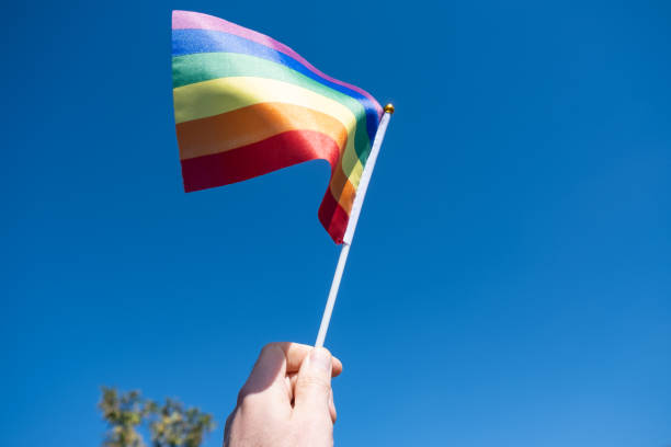 istock LGBT flag in a man's hand against a blue sky background 1279945227