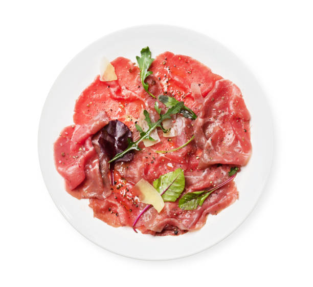 Marbled beef carpaccio Marbled beef carpaccio with arugula, spices and parmesan cheese. Top view flat lay isolated on white carpaccio parmesan cheese beef raw stock pictures, royalty-free photos & images