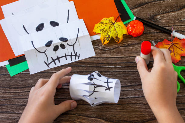 istock Instruction step 6. Child creates Halloween decor, paper lanterns garland skull for Halloween. Childrens art project, crafts, fun activities for kids. 1279946741