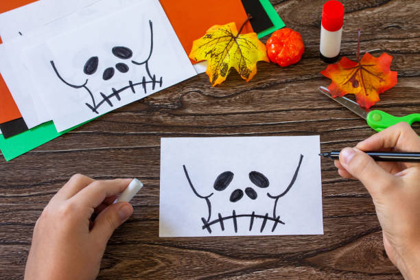 istock Instruction step 4. Child creates Halloween decor, paper lanterns garland skull for Halloween. Childrens art project, crafts, fun activities for kids. 1279946748