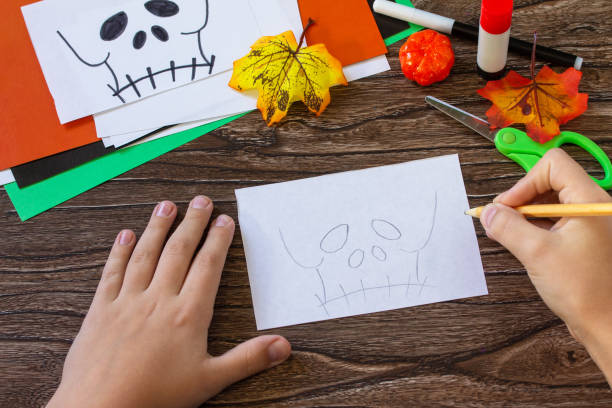 istock Instruction step 3. Child creates Halloween decor, paper lanterns garland skull for Halloween. Childrens art project, crafts, fun activities for kids. 1279946749