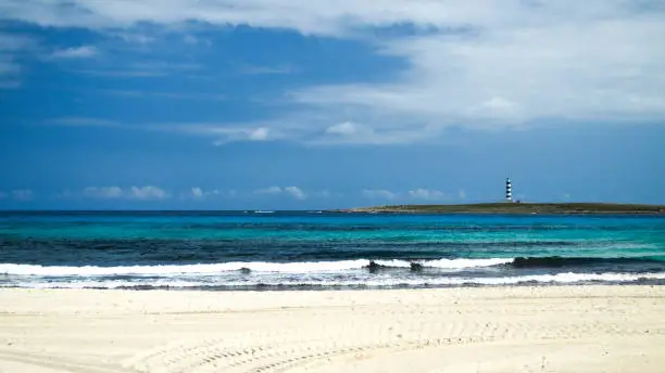 View from the platja of Punta Prima in Menorca of the Isla del Aire and its lighthouse.