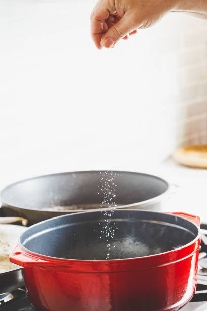 istock Man's hand putting salt while cooking food 1279950409