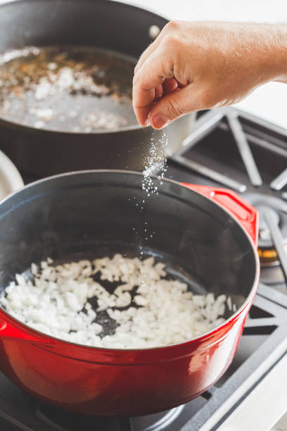 istock Man's hand putting salt while cooking white onion 1279950581