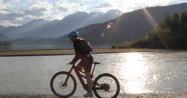 istock Female mountain e-biker rides along lakeshore at sunrise 1279951330