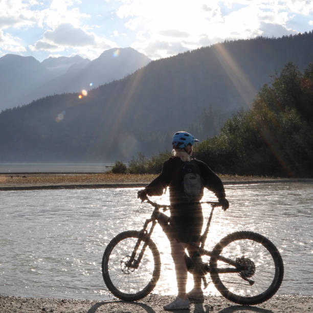 istock Female mountain e-biker relaxes by lakeshore at sunrise 1279951989