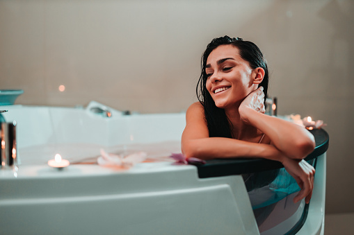 Young woman wearing swimwear relaxing and enjoying luxury hotel bathtub