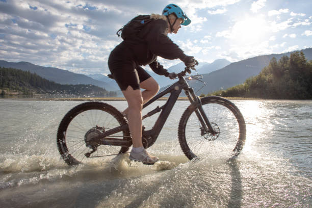 istock Female mountain e-biker rides along lakeshore at sunrise 1279952803