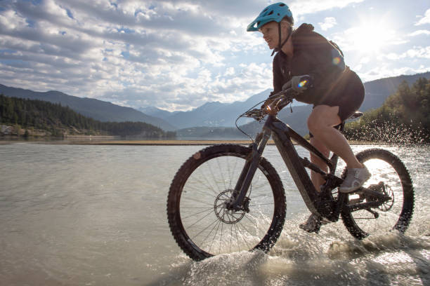 istock Female mountain e-biker rides along lakeshore at sunrise 1279952894