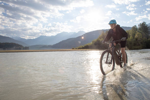 istock Female mountain e-biker rides along lakeshore at sunrise 1279953477