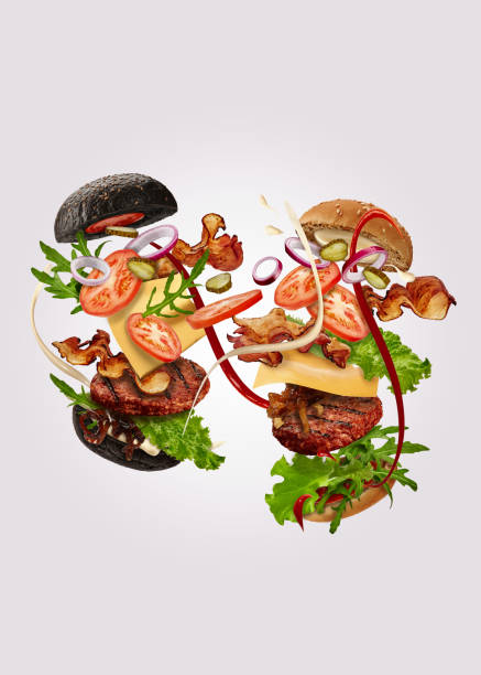 dwa burgery, czarne i klasyczne, z latającymi składnikami na szarym tle. szynka, kotlet wołowy, ser, sosy, warzywa i warzywa. zbliżenie - food elegance cutlet restaurant zdjęcia i obrazy z banku zdjęć