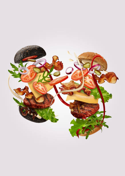 two burgers, black and classic, with flying ingredients against gray background. ham, beef cutlet, cheese, sauces, vegetables and greens. close up - food elegance cutlet restaurant imagens e fotografias de stock