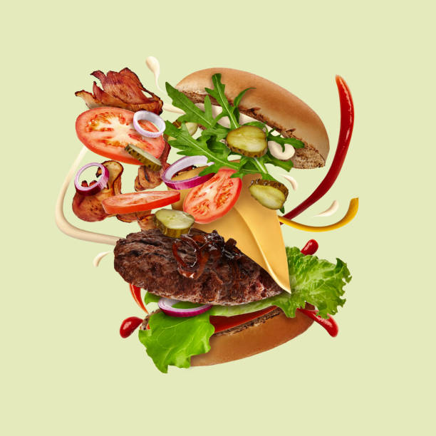 istock Appetizing big burger with flying ingredients against pale green background. Ham, beef cutlet, cheese, sauces, vegetables and greens. Close up 1279953518