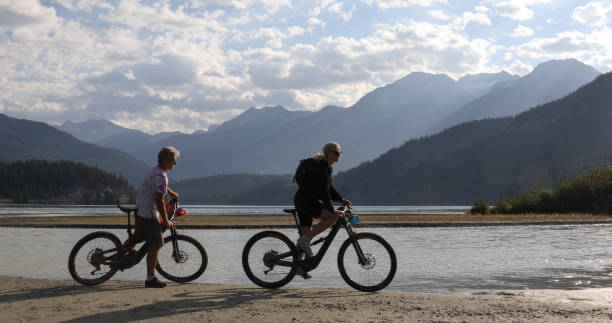 istock Couple on e-bikes ride along lakeshore at sunrise 1279953644