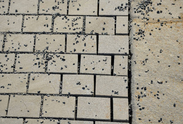 istock laying granite and marble light, white gray, medium size cubes. tilers put cobblestones in sand or gravel. they have piles ready to lay or wooden pallets occupy the passage on the sidewalk 1279955116