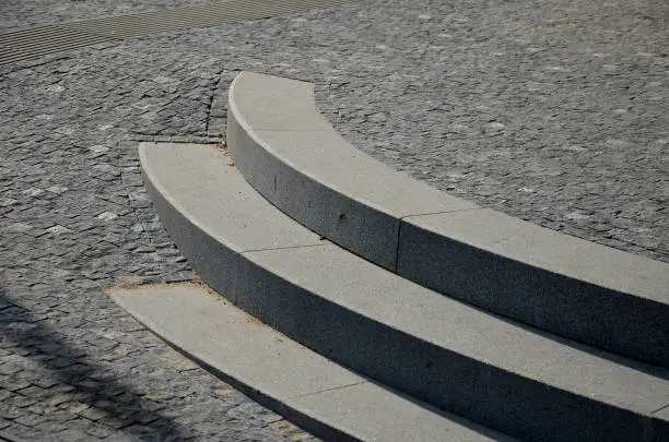 3, rows, stairs, stair, square,  gradually, sunk, paving, Slow, transition, staircase, plane, blending, intersecting, granite, marble, entrance, building, gray, stone, cubes, mosaic, cobblestone, pavement, detail, construction, massive, bent, curved, curve, light, rock, step, straight, lines, architecture